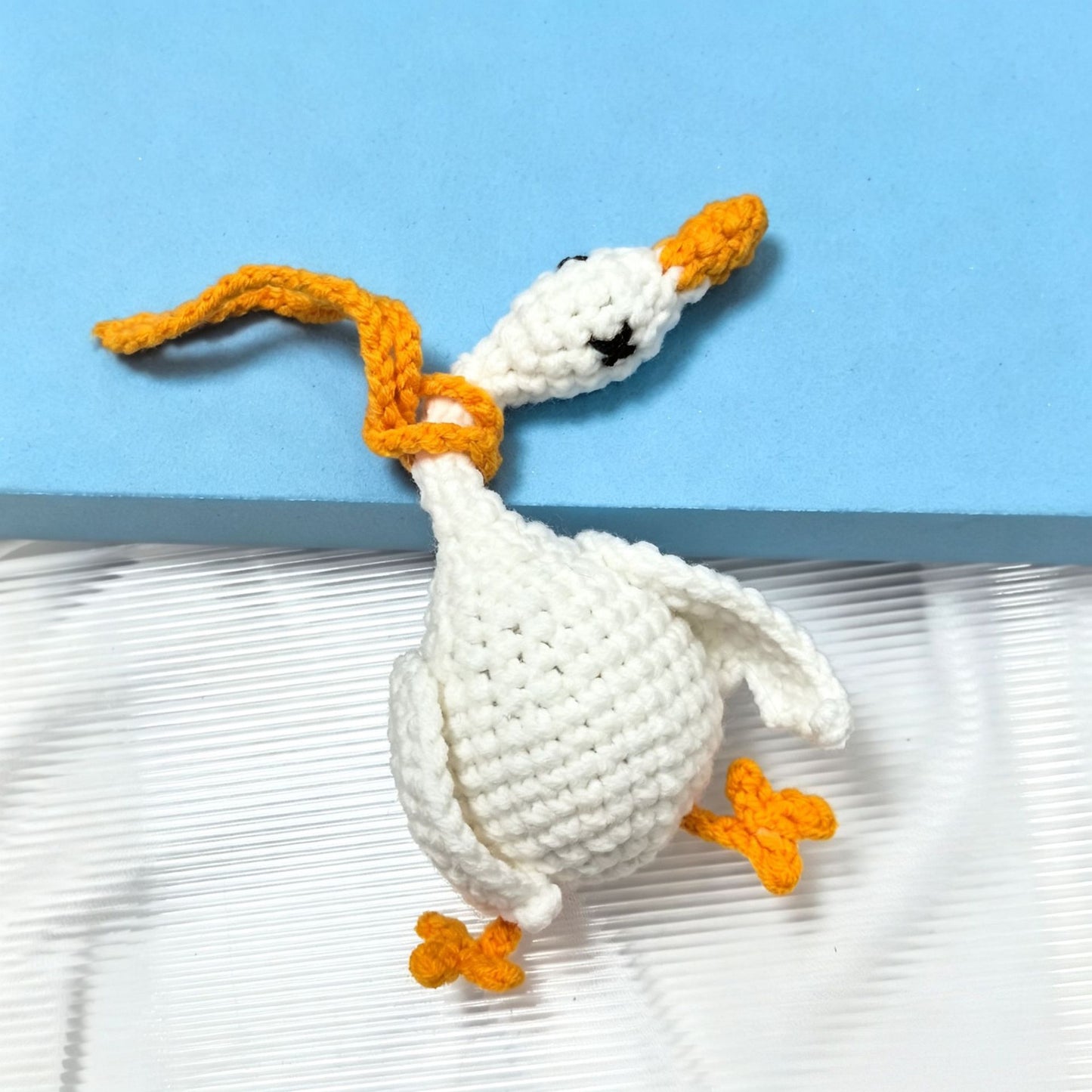 Hand-knitted keychain of a silly long-necked white goose with a crooked neck